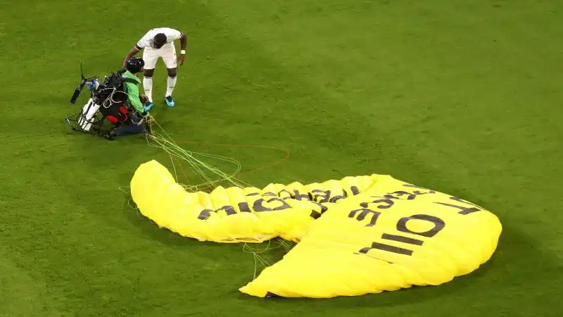 Prima del fischio di inizio della partita un paracadutista di Greenpeace atterra sul campo di gioco tra lo stupore di tutti
