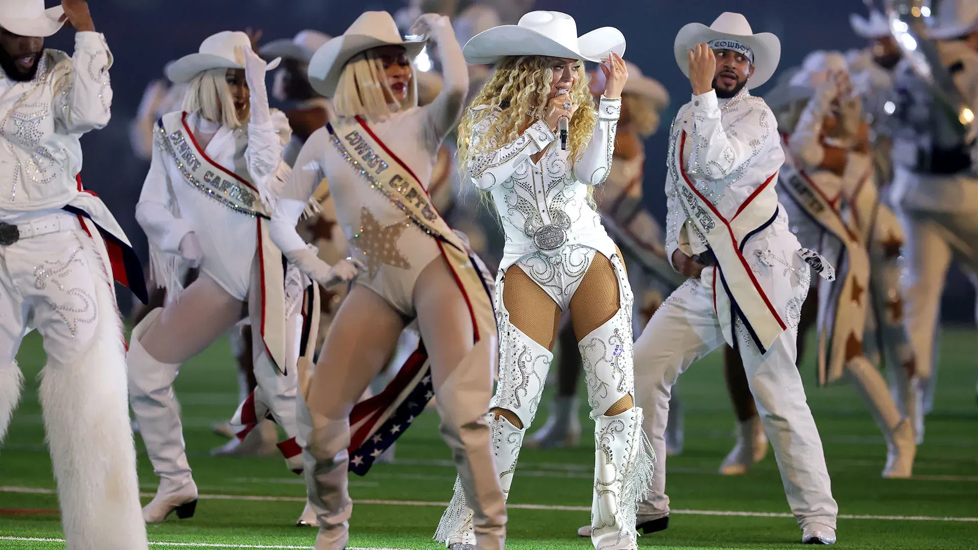 Un body bianco scollato e un cappello da cowboy, abbinato a gambali in pelle